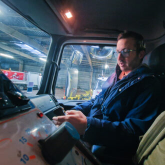 Un homme assis dans la cabine d'un camion de déneigement.