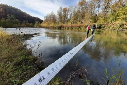 Un homme et une femme en cuissarde au milieu d'une rivière prennent des mesures dans l'eau. - Agrandir l'image, fenêtre modale
