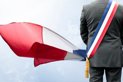 Un homme de so portant une écharpe d'élu aux couleurs de la France et un drapeau français. - Agrandir l'image, fenêtre modale