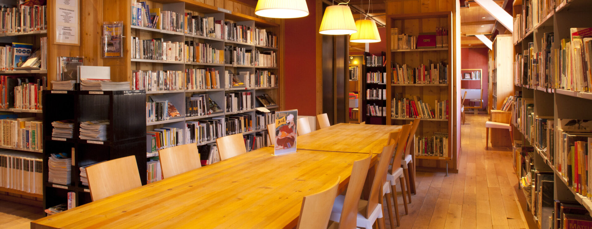 Salle de lecture entourée d'étagères remplies de livres dans une bibliothèque