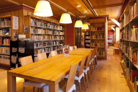 Salle de lecture entourée d'étagères remplies de livres dans une bibliothèque