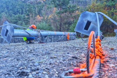 Un ouvrier en gilet fluo accroupi en train d'étudier des poteaux métalliques posés au sol - Agrandir l'image 20 sur 27, fenêtre modale