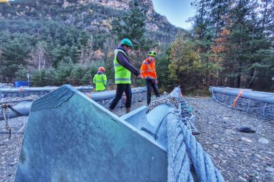Des ouvriers en gilet fluo en train d'étudier des poteaux métalliques posés au sol - Agrandir l'image 19 sur 27, fenêtre modale