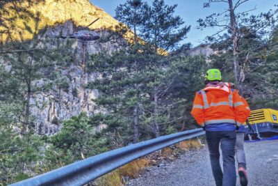 Deux hommes en gilet orange fluo et casque de chantier sur la tête marche sur une route de montagne - Agrandir l'image 15 sur 27, fenêtre modale