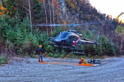 Un hélicoptère en train de se poser sur une zone de chantier, les montagne en arrière plan. - Agrandir l'image 27 sur 27, fenêtre modale