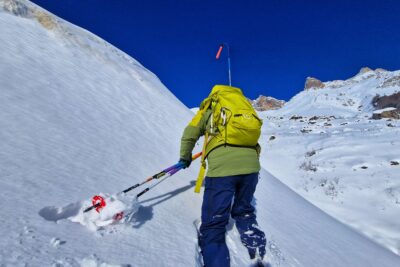 Un homme de dos sac à dos sur le dos, bâtons de ski à la main évolue dans le neige. Au fond, les montagnes enneigées. - Agrandir l'image 1 sur 13, fenêtre modale