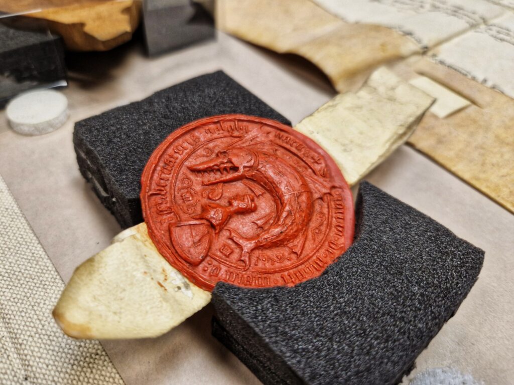 Reposant sur une mousse noire, une seau de cire rouge représentant un dauphin - Agrandir l'image, fenêtre modale