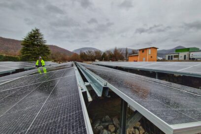 Un agent du Département en veste de chantier jaune fluo évolue au milieu d'une mer de panneaux photovoltaïque. Au dernier plan on aperçoit la nouvelle station d'épuration de Veynes. - Agrandir l'image, fenêtre modale