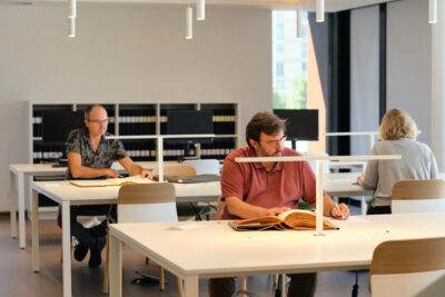 Des usagers consultent des ouvrages dans la nouvelle salle de lecture des Archives départementales - Agrandir l'image 4 sur 9, fenêtre modale