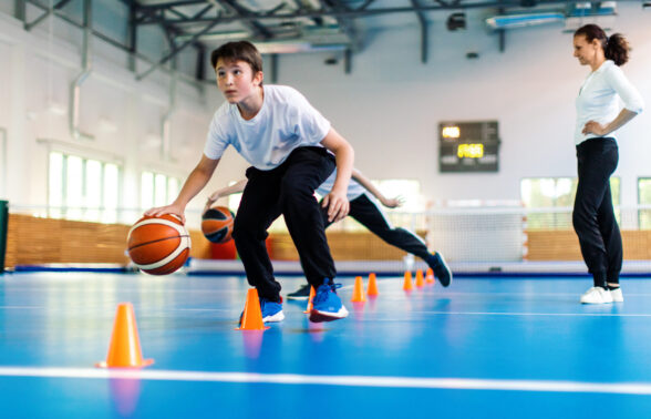 Jeune collégien pratiquant le basket dans un gymnase