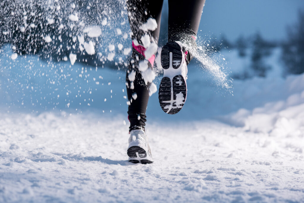Au milieu de la photo, on voit le bas d'une paire de jambes appartenant certainement à une femme en legging noir et basket en train de courir sur le neige. La coureuse est en train de s'éloigner de nous. - Agrandir l'image, fenêtre modale