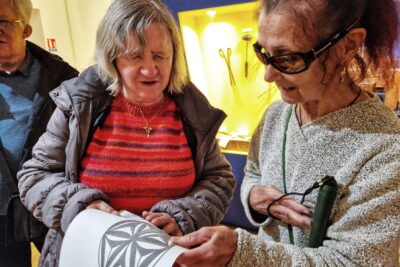 Deux femmes aveugles touchent une rosace typique du Queyras reproduite via la méthode de thermo gonflage. - Agrandir l'image 5 sur 13, fenêtre modale