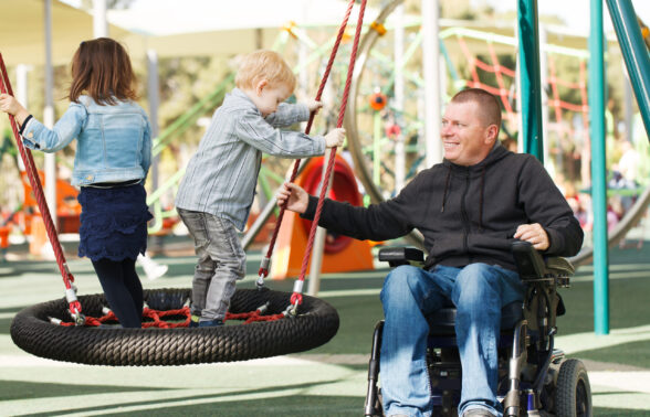 Père en fauteuil roulant jouant avec ses enfants dans un parc