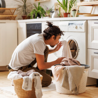 Homme triant le linge devant sa machine à laver